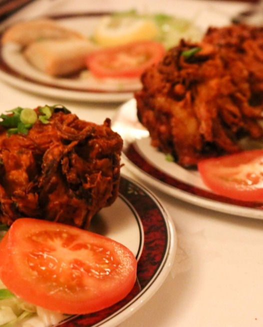 Two plates with onion bhajis on garnished with tomato and lettuce