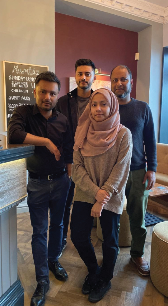 Family standing by the bar in their Indian restaurant