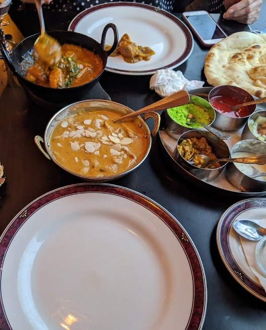 Close up of a waiter dressed in white shirt with tie and black jacket with 'Mumtaz' written on his top jacket pocket